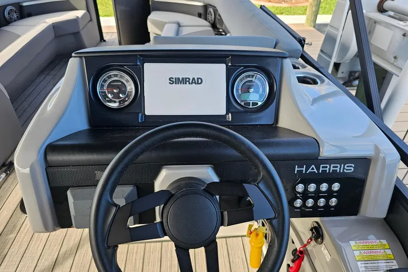 Slide: The Image of 2024 Harris boat dashboard with Simrad display and steering wheel. - 10