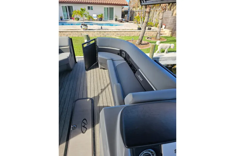 Slide: The Image of 2024 Harris boat interior with gray seating, docked near a poolside patio. - 19