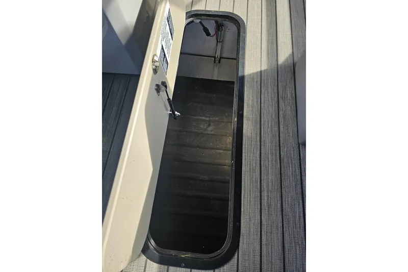 Slide: The Image of Open storage compartment on a 2024 Harris boat, featuring a sleek black interior. - 24