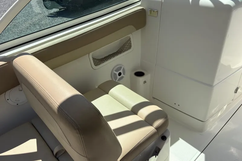 Slide: The Image of Interior seating of a 2017 Sailfish 245 DC boat, featuring beige upholstery and cup holder. - 11