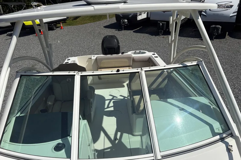 Slide: The Image of 2017 Sailfish 245 DC boat interior with seating and windshield, parked on gravel. - 21