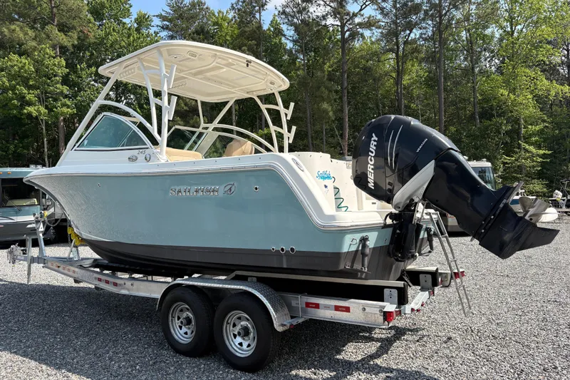 Slide: The Image of 2017 Sailfish 245 DC boat on trailer with Mercury outboard, parked outdoors. - 26