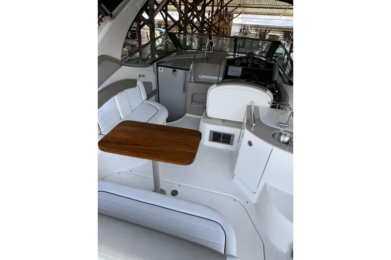 Slide: The Image of 2007 Sea Ray 290 Sundancer interior with seating, wooden table, and helm controls. - 10