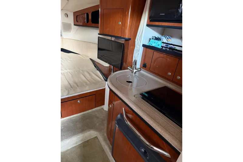 Slide: The Image of Interior of 2007 Sea Ray 290 Sundancer, featuring kitchenette and cozy sleeping area. - 12