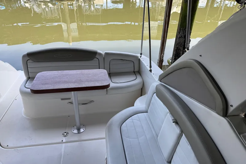 Slide: The Image of 2007 Sea Ray 290 Sundancer boat interior with seating and table, docked by calm water. - 7