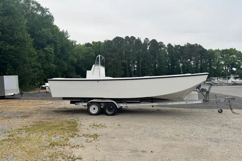 The Image of 2026 Jennings 26 Garvey boat on trailer, parked outdoors near forested area. - 1