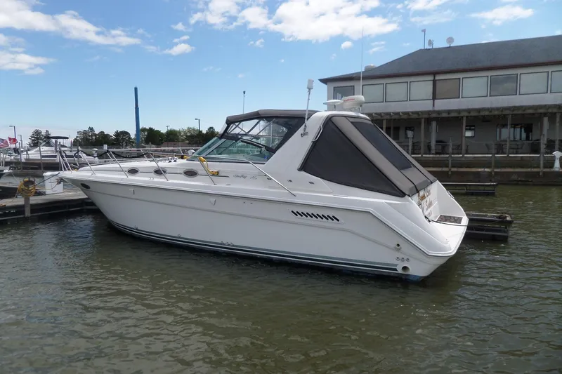 Slide: The Image of 1994 Sea Ray 370 Express Cruiser docked at a marina under a partly cloudy sky. - 1