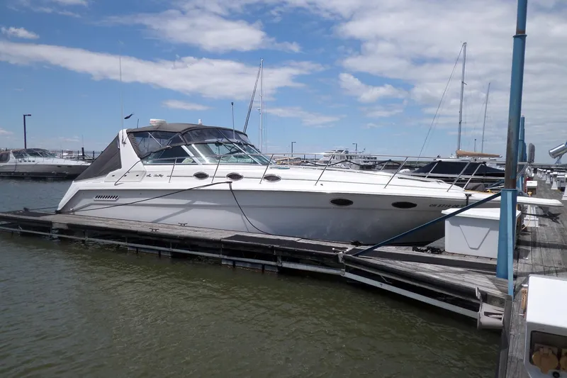 The Image of 1994 Sea Ray 370 Express Cruiser docked at marina under blue sky. - 2
