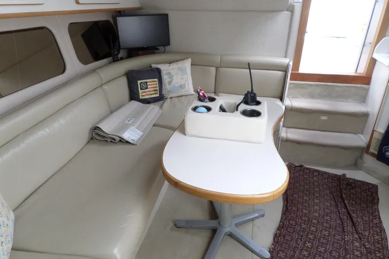 Slide: The Image of 1994 Sea Ray 370 Express Cruiser interior with beige seating, table, and nautical decor. - 35