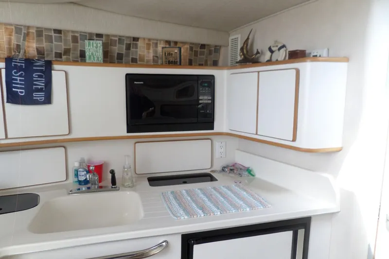 Slide: The Image of 1994 Sea Ray 370 Express Cruiser kitchen with sink, microwave, and decorative signs. - 40