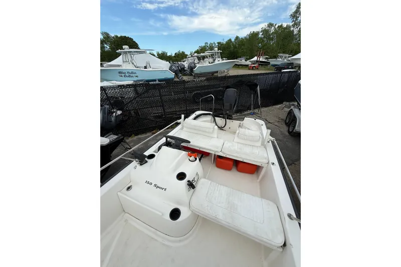 Slide: The Image of 2006 Boston Whaler 150 Sport boat interior with seating and storage, docked outdoors. - 10