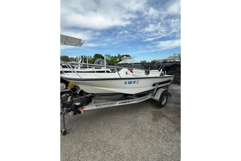 Slide: The Image of 2006 Boston Whaler 150 Sport boat on trailer under a partly cloudy sky. - 2