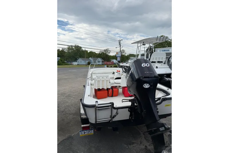 Slide: The Image of 2006 Boston Whaler 150 Sport boat with outboard motor, parked outdoors. - 5