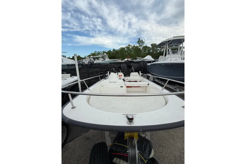 Slide: The Image of 2006 Boston Whaler 150 Sport boat on trailer, parked outdoors under cloudy sky. - 7