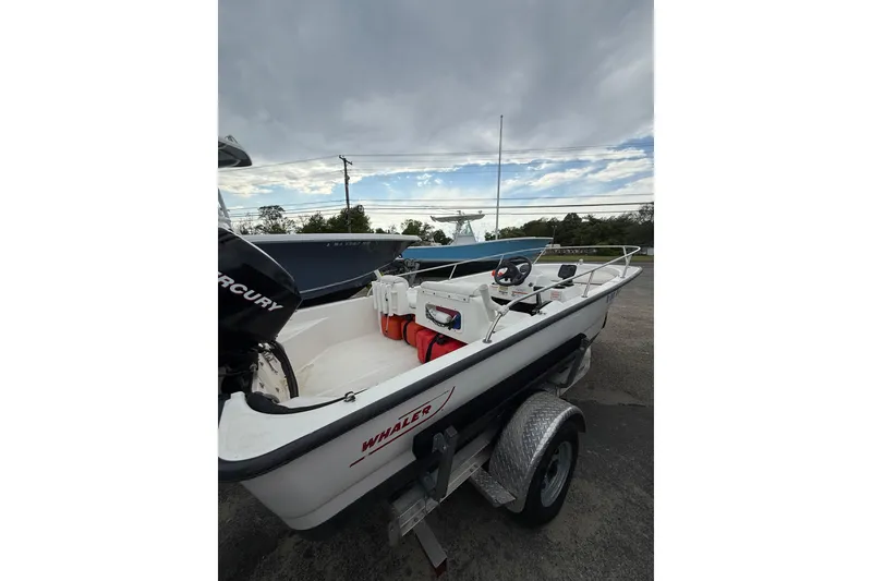 Slide: The Image of 2006 Boston Whaler 150 Sport boat on trailer, featuring Mercury engine under cloudy sky. - 8