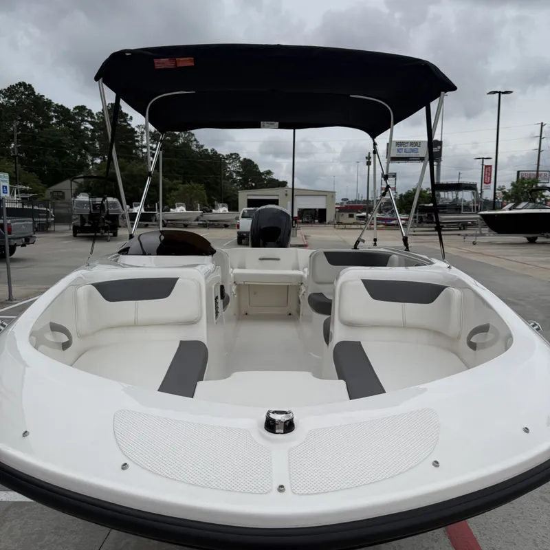 Slide: The Image of 2025 Bayliner E18LE boat with Bimini top on parking lot. - 19