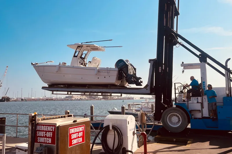 Slide: The Image of 2023 World Cat 235 CC boat lifted by forklift at marina dock. - 2