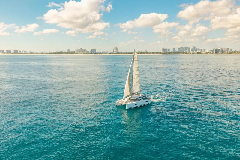 Slide: The Image of 2019 Fountaine Pajot 47 sailing on open sea with city skyline in background. - 2