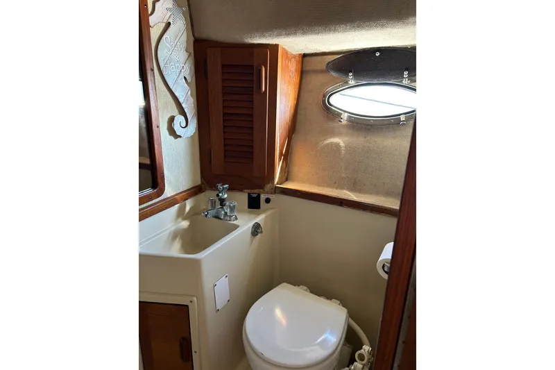 Slide: The Image of 1987 Tiara Yachts 3100 Open bathroom with sink, toilet, and porthole window. - 11