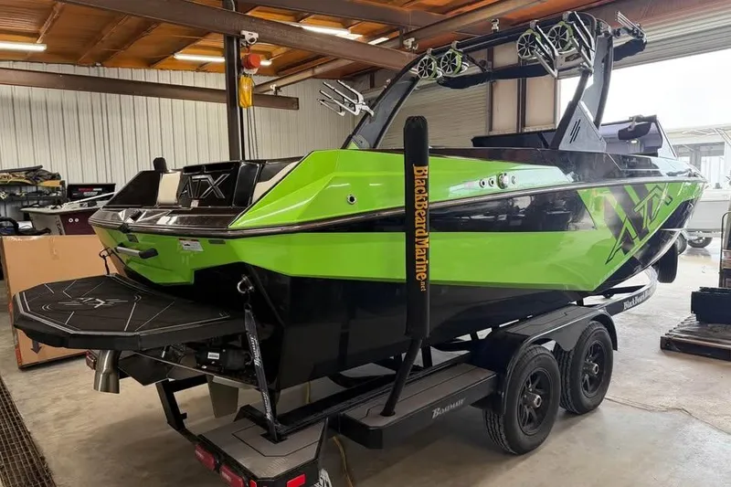 Slide: The Image of 2022 ATX Surf Boats 24 Type-S in vibrant green and black, parked indoors on a trailer. - 5