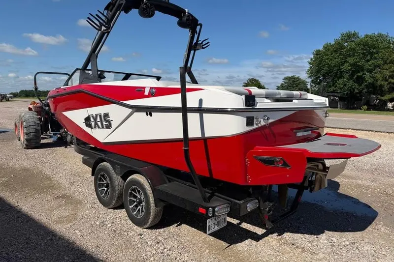 Slide: The Image of Red and white 2022 Axis T220 boat on trailer, parked outdoors under a clear sky. - 2