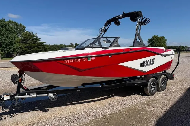 Slide: The Image of 2022 Axis T220 boat in red and white on a trailer, parked outdoors. - 4