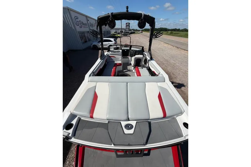 Slide: The Image of 2022 Axis T220 boat with sleek design, red and gray seating, parked outdoors. - 6