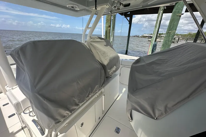 Slide: The Image of 2021 Pursuit S 328 Sport boat interior with covered seats, docked by the water. - 13