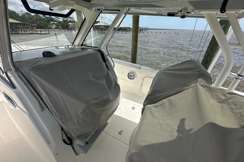 Slide: The Image of 2021 Pursuit S 328 Sport boat interior with covered seats by the water. - 15