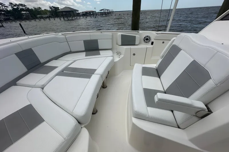 Slide: The Image of 2021 Pursuit S 328 Sport boat interior with gray and white seating, near waterfront. - 25
