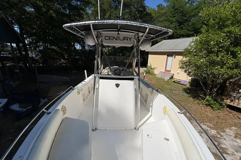 Slide: The Image of 2005 Century 2200 Center Console boat with T-top, parked outdoors near trees and a house. - 10