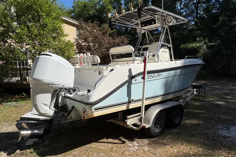 Slide: The Image of 2005 Century 2200 Center Console boat on trailer, parked outdoors in a wooded area. - 4