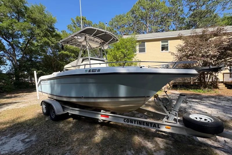 Slide: The Image of 2005 Century 2200 Center Console boat on trailer, parked outdoors near a house. - 6