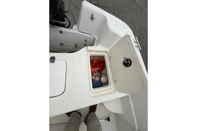 Slide: The Image of Open storage compartment on a 2008 Carolina Skiff 218 DLV boat, containing various items. - 16