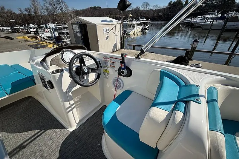 Slide: The Image of 2022 Bayliner Element E18 boat interior with steering wheel and blue seating at marina. - 10