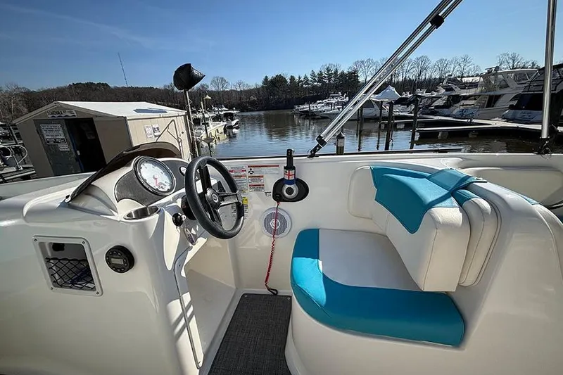 Slide: The Image of 2022 Bayliner Element E18 boat interior with steering wheel and blue seating at marina. - 11