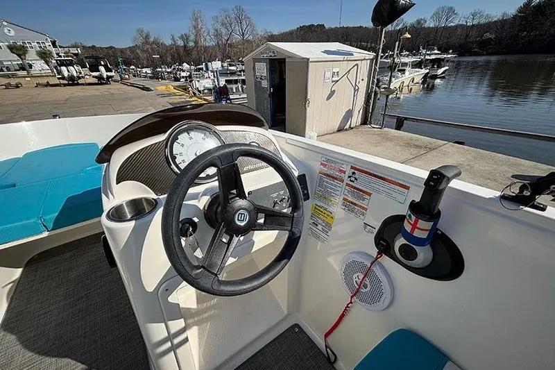 Slide: The Image of 2022 Bayliner Element E18 boat dashboard with steering wheel, docked at marina. - 12