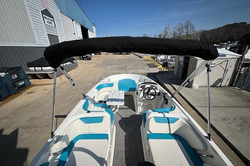 Slide: The Image of 2022 Bayliner Element E18 boat with blue seating and canopy at a marina. - 5