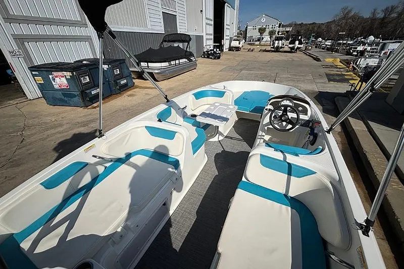 Slide: The Image of 2022 Bayliner Element E18 boat interior with blue and white seating, docked at a marina. - 6