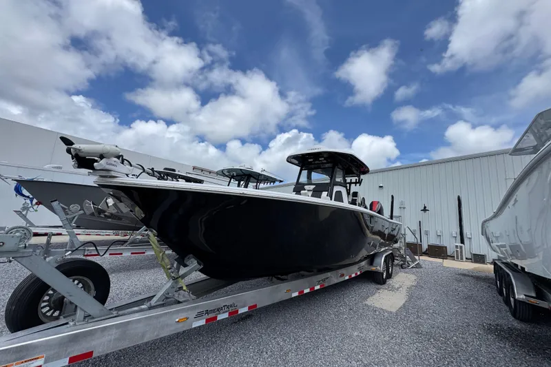 Slide: The Image of 2024 Tidewater 3100 Carolina Bay boat on trailer, parked outdoors under a cloudy sky. - 2