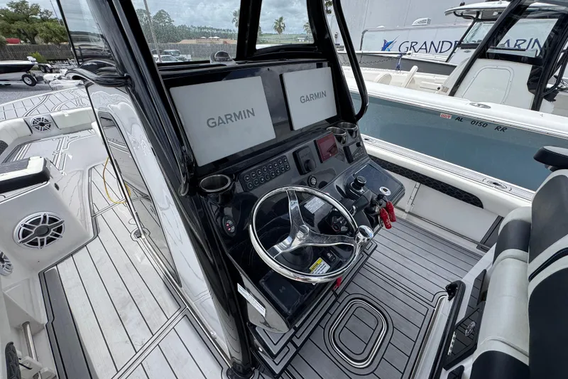 Slide: The Image of 2024 Tidewater 3100 Carolina Bay boat cockpit with Garmin navigation system and sleek steering wheel. - 25