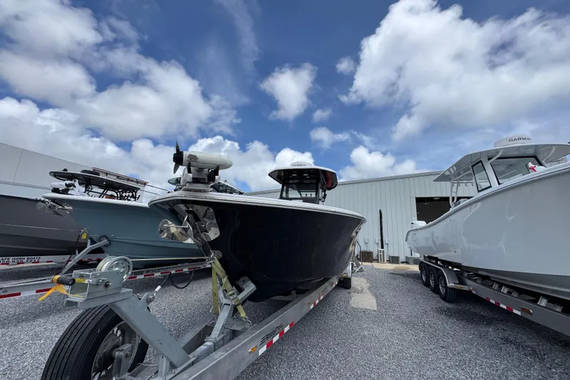 Slide: The Image of 2024 Tidewater 3100 Carolina Bay boat on trailer, parked outdoors under a cloudy sky. - 3