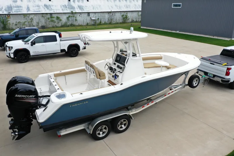 Slide: The Image of 2016 Tidewater 252 CC Adventure boat on trailer, parked beside trucks. - 3