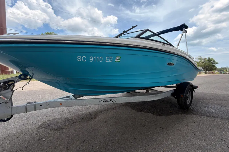 Slide: The Image of 2021 Sea Ray SPX 190 boat on trailer, blue hull, parked on road under cloudy sky. - 7