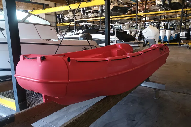 The Image of Red 2024 Whaly 455R boat displayed in a storage facility with other boats. - 0