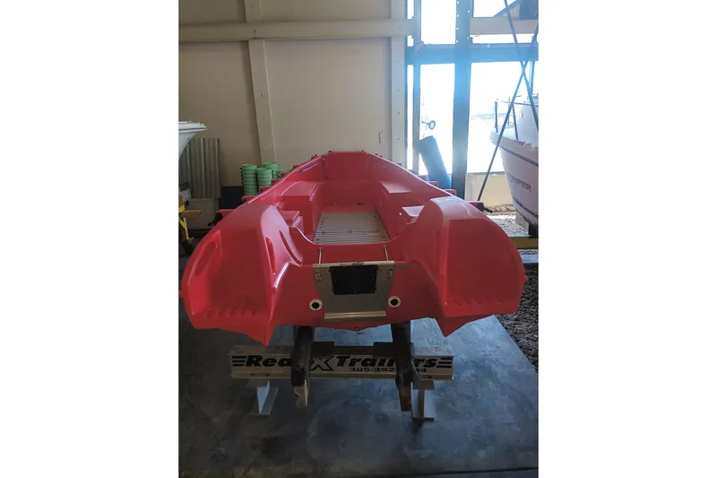 Slide: The Image of 2024 Whaly 455R red boat displayed indoors on a trailer. - 7