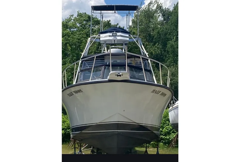 Slide: The Image of 1988 Rampage 31 Express boat on land, surrounded by trees, under a clear sky. - 2
