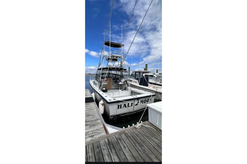 Slide: The Image of 1988 Rampage 31 Express boat docked at marina under clear blue sky. - 4