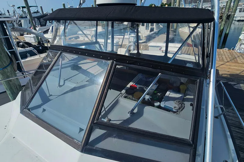 Slide: The Image of 1988 Rampage 31 Express boat docked, featuring a covered cockpit and clear windshield. - 9