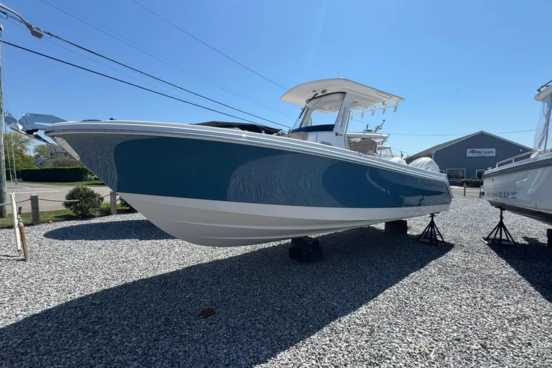 Slide: The Image of 2026 Edgewater 262CC boat displayed outdoors on gravel lot under clear blue sky. - 1